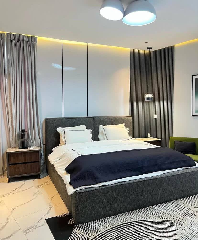 A bedroom with twin dome pendants over the bed and a slatted wood accent wall